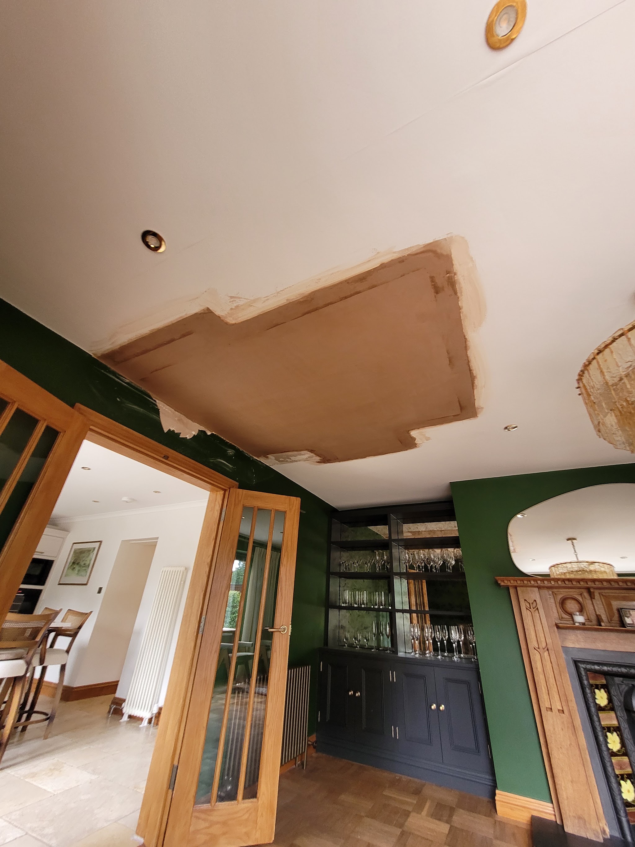 Freshly skimmed ceiling repair in a dining room, still pink while it dries