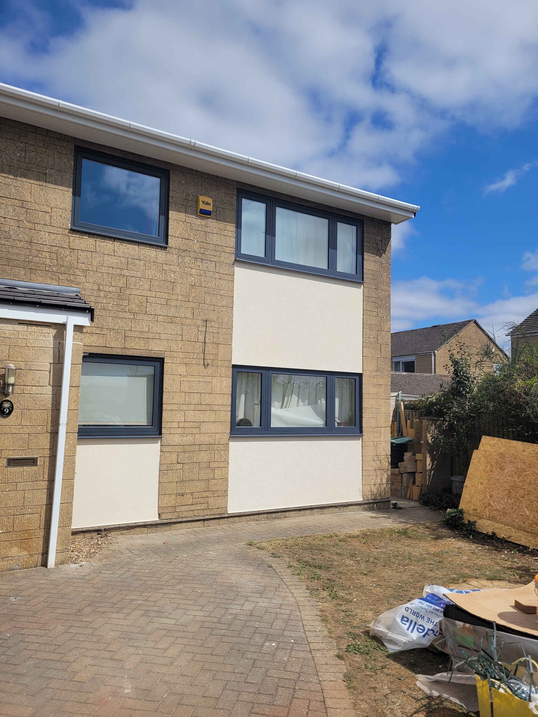 Two storey house with smooth cream render between sections of Cotswold stone