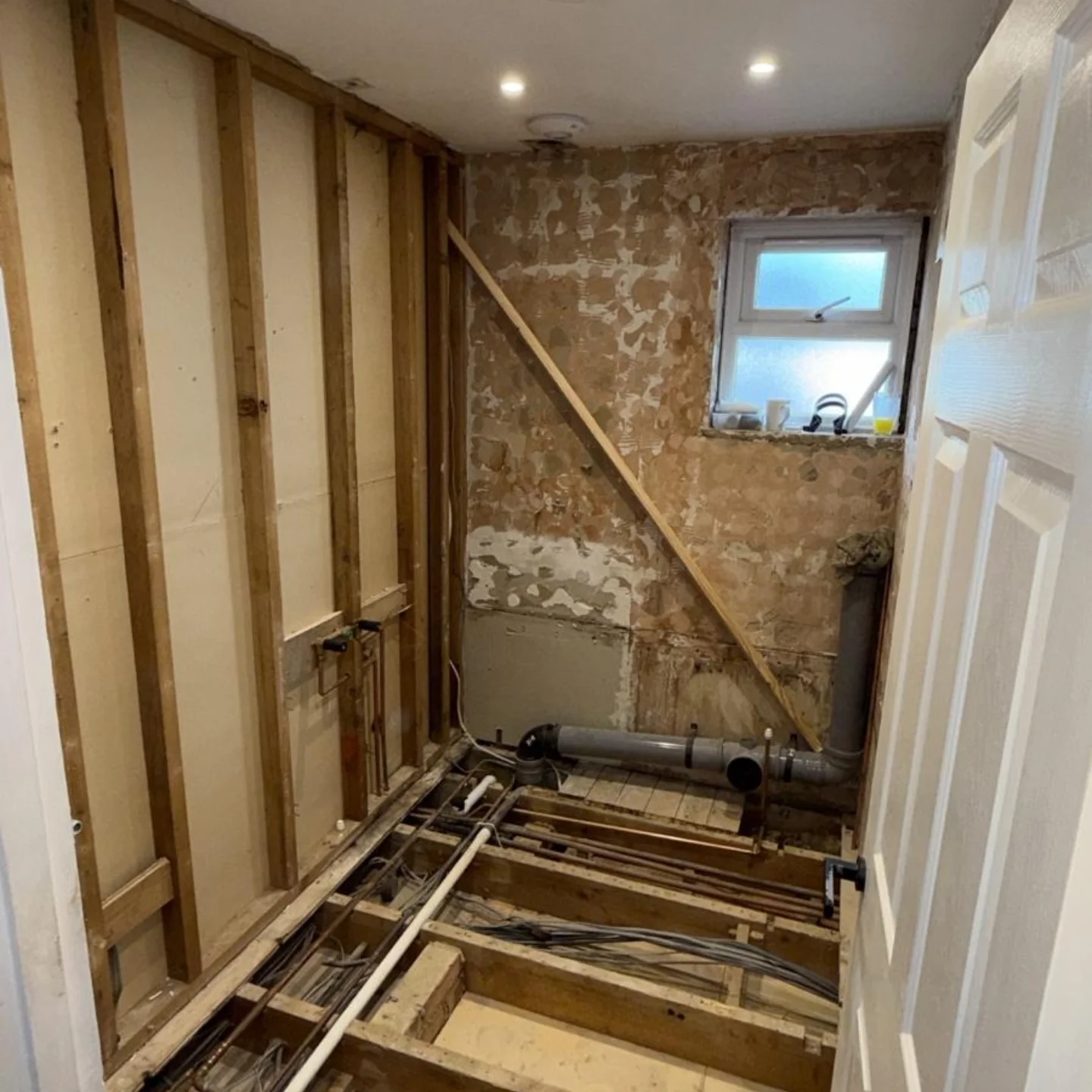 Bathroom stripped back to studwork and old plaster, before plastering